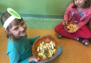 Dziewczynki jedzą przygotowane przez siebie sałatki.